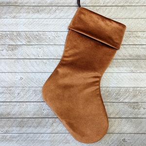 Puede incluir: Una media de Navidad de terciopelo marrón con un puño doblado.