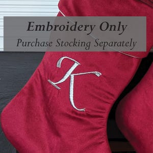 Puede incluir: Primer plano de un calcetín navideño rojo con una letra "K" bordada en blanco. El calcetín tiene un ribete blanco y el texto "Embroidery Only Purchase Stocking Separately".