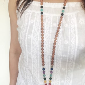 May include: A wooden mala necklace with a tassel. The necklace features colourful beads and a silver charm.