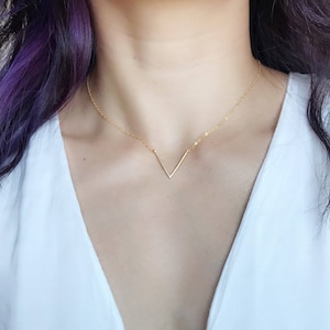 Puede incluir: Un collar de oro con un colgante simple en forma de V.