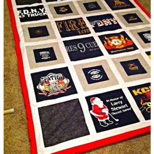 May include: A handmade quilt featuring squares of various firefighter-themed t-shirts. The quilt has a red border and white and gray squares. Some shirts display text like "FIRE", "KCFD", and "F.D.N.Y. 43 TRUCK".