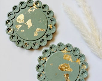 May include: Two round green coasters with gold leaf accents and a decorative scalloped edge.