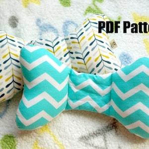 Peut inclure: Un patron PDF pour un coussin en forme de nœud avec un motif chevron turquoise et blanc. Le coussin est composé de deux pièces distinctes qui sont cousues ensemble pour créer la forme du nœud. Le patron est disponible en téléchargement.