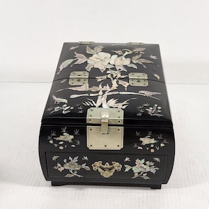 以下が含まれることがあります： 真珠貝で象嵌された花柄の黒い木製のジュエリーボックス。箱は蝶番付きの蓋と引き出しが付いています。