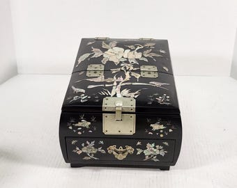 Pode incluir: Uma caixa de madeira preta para joias com um design floral incrustado de madrepérola. A caixa tem uma tampa com dobradiças e uma gaveta.