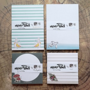 May include: Four memo pads with different designs. One pad has a banana graphic and the word "BANANA". Another has a turtle illustration and the word "Skilpadde". The third pad has a mushroom graphic and the words "Fly Agaric". The last pad has a moth graphic and the word "Mall".