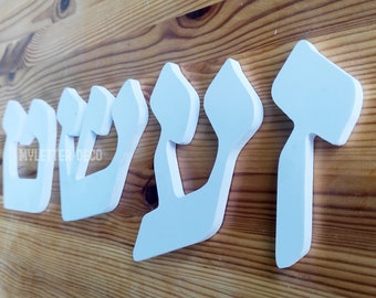 May include: White wooden letters spelling out the Hebrew word "Shalom" in a 3D style. The letters are arranged in a row on a wooden surface.