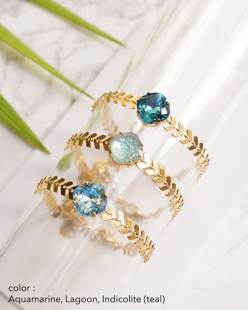 Puede incluir: Tres anillos dorados con una banda de patr&oacute;n de espiga y una piedra &uacute;nica de corte coj&iacute;n facetado. Las piedras son de color aguamarina, laguna y azul verdoso indicolita. El texto en la parte inferior dice: color: Aquamarine, Lagoon, Indicolite (teal).