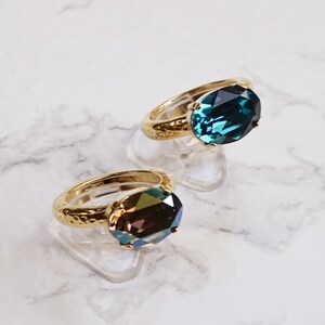 May include: Two rings with gold-toned hammered bands and oval-cut faceted stones. One ring features a deep blue indicolite stone, while the other displays a metallic bronze stone. The text Bronze and indicolite appears at the bottom.