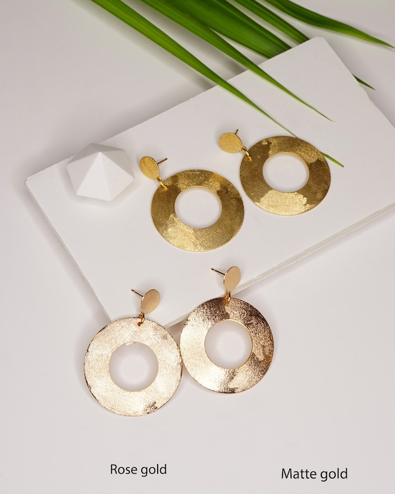 May include: Two pairs of gold hoop earrings with a hammered texture. The top pair is rose gold and the bottom pair is matte gold.