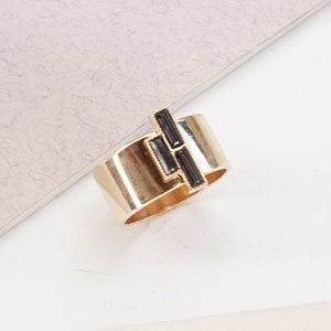 Puede incluir: Un anillo de oro rosa con un dise&ntilde;o geom&eacute;trico negro. El anillo est&aacute; sobre una superficie blanca. SILVER NIGHT | ROSE GOLD