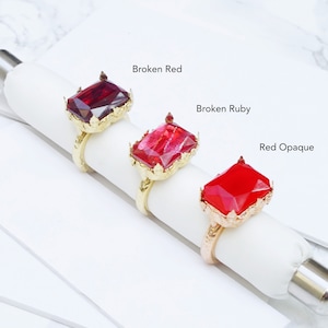K&ouml;nnte beinhalten: Drei goldene Ringe mit verschiedenen roten Edelsteineins&auml;tzen. Die Ringe sind mit "Broken Red", "Broken Ruby" und "Red Opaque" beschriftet.