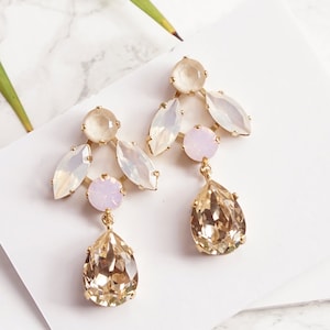 May include: A pair of gold earrings with a teardrop-shaped crystal and a cluster of white and pink opal stones.  White opal & Silk.
