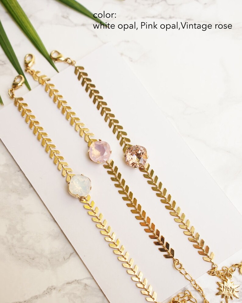 Puede incluir: Tres pulseras de tono dorado con un dise&ntilde;o de cadena de espiga y una piedra facetada individual. Las piedras est&aacute;n disponibles en colores &oacute;palo blanco, &oacute;palo rosa y rosa vintage. Cada pulsera incluye un cierre de mosquet&oacute;n y una cadena extensora.