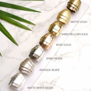 May include: A collection of six metal rings arranged in a row on a white card, labeled FINISH SAMPLE TO CHOOSE. The finishes include matte gold, shiny yellow gold, rose gold, shiny silver, antique silver, and matte white silver.
