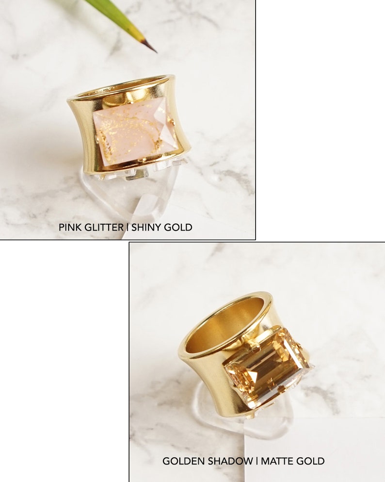 May include: Two rings with wide bands. The top ring is shiny gold with a rectangular pink glitter stone, labeled PINK GLITTER | SHINY GOLD. The bottom ring is matte gold with a rectangular amber-colored stone, labeled GOLDEN SHADOW | MATTE GOLD.