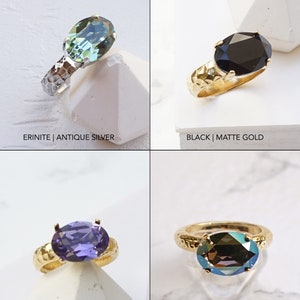 May include: Four rings with oval-cut faceted stones. Top left: Erinite stone with antique silver hammered band. Top right: Black stone with matte gold hammered band. Bottom left: Tanzanite stone with matte gold band. Bottom right: Bronze shade stone with matte gold band.