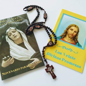 May include: A brown wooden rosary with a crucifix and a small booklet with the title "Oraciones Santo Rosario" and "Novenario Para Difuntos" and a yellow booklet with the title "Las Veinte Divinas Promesas".
