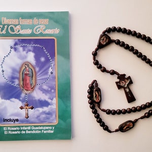 May include: A brown wooden rosary with a crucifix and beads featuring images of the Virgin Mary. A green booklet titled "El Santo Rosario" with instructions on how to pray the rosary is also included. The booklet features an image of the Virgin Mary and a crucifix.