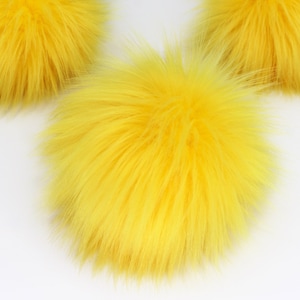 May include: Three fluffy yellow pom poms, perfect for adding a touch of whimsy to crafts or clothing.