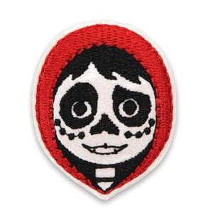 May include: Embroidered patch featuring a cartoon character with a white skull face, black hair, and a red hood. The character is smiling with large eyes.