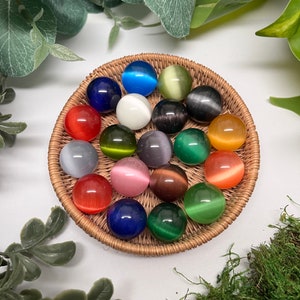 Fiber Optic glass marbles, not see-through. Cats eye effect. All colors. All sitting on a woven basket tray, backround is white with leaves and moss. Pouch is black velvetine. Includes information card in a brown box with copper bow and caveman logo