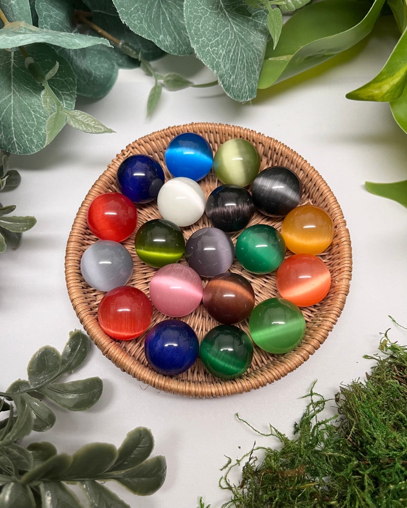 Fiber Optic glass marbles, not see-through. Cats eye effect. All colors. All sitting on a woven basket tray, backround is white with leaves and moss. Pouch is black velvetine. Includes information card in a brown box with copper bow and caveman logo