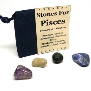 Könnte beinhalten: Ein Set aus vier Trommelsteinen in einem kleinen blauen Beutel. Die Steine sind Amethyst, Aquamarin, Blutstein und Sodalith. Der Beutel hat ein Etikett mit der Aufschrift "Stones For Pisces February 19 - March 20 Amethyst - Intuition Aquamarine - Emotional Insight Bloodstone - Grounding Sodalite - Logical Thought".