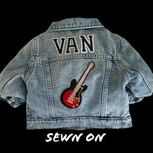 May include: A light blue denim jacket with a black and white "VAN" patch and a red and gold guitar patch sewn on the back. The text "SEWN ON" is printed below the patches.