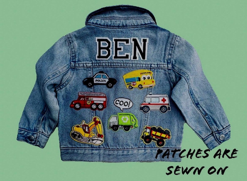 May include: A blue denim jacket with various colorful patches sewn on. The patches feature a school bus, a police car, a fire truck, a dump truck, a construction vehicle, a garbage truck, and a first aid vehicle. The jacket has the name "BEN" sewn on the back.