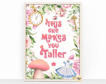 May include: A framed print with an Alice in Wonderland theme. The artwork features a pocket watch, teapot, key, mushroom, dress, and the text "This One Makes You Taller" in pink. Floral elements frame the text.