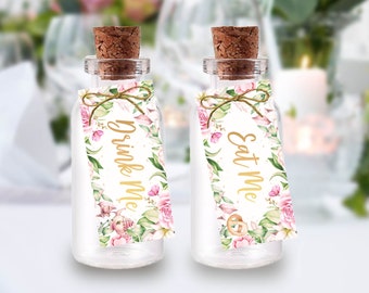 Könnte beinhalten: Zwei kleine Glasflaschen mit Korkstopfen und floralen Etiketten. Die Etiketten haben goldene Schriftzüge mit der Aufschrift "Drink Me" und "Eat Me".