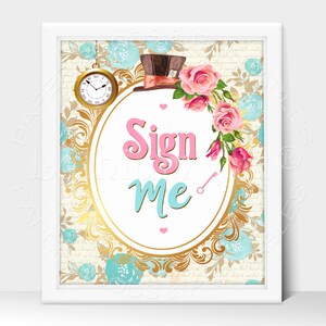 May include: A white framed sign with a gold oval border and a white background. The sign says "Sign Me" in pink and blue lettering. The oval border is decorated with a floral pattern of pink roses and blue flowers. A top hat with a red and white ribbon is at the top of the sign.
