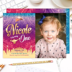 May include: A purple, blue, and pink invitation with a gold border and a picture of a young girl. The invitation says "Nicole is turning One" and has a genie lamp graphic. The text also includes the date, time, and location of the event.