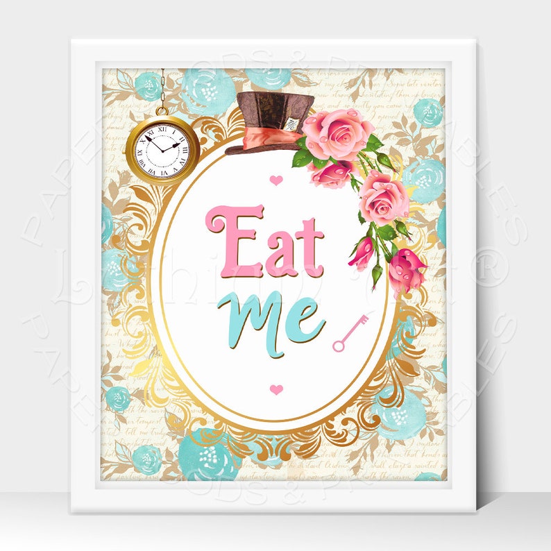 May include: A white framed print with a gold ornate oval frame. The frame has a white background with the words "Eat Me" in pink and blue lettering. The frame is decorated with a blue and gold floral pattern and a small gold key. A top hat with a red and white band is in the upper left corner of the image.