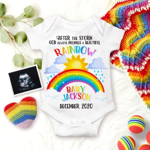 May include: White baby onesie with a rainbow, clouds, sun, and raindrops. The text reads "After the storm God always promises a beautiful rainbow Baby Jackson December 2020".