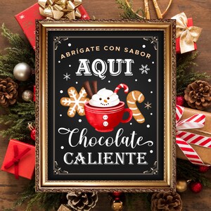 Puede incluir: Un cartel de pizarra enmarcado con un marco dorado, que presenta una ilustración festiva de un muñeco de nieve sosteniendo una taza de chocolate caliente. El cartel dice "Abrigate con sabor Aqui Chocolate Caliente".