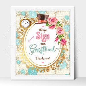 May include: A white frame with a gold ornate oval sign that says "Please Sign the Guestbook Thank you!" with a pink heart. The sign is surrounded by pink and white roses, a blue pocket watch, and a blue and brown top hat.
