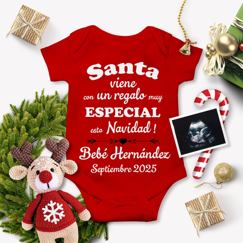 May include: Red baby onesie with white text that reads "Santa viene con un regalo muy ESPECIAL esta Navidad! Bebe Hernandez Septiembre 2025". There is a small ultrasound image and a candy cane in the background.