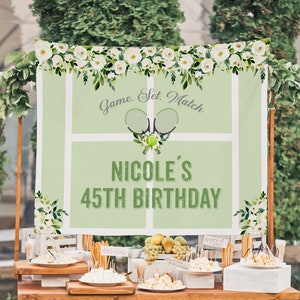 Peut inclure: Une toile de fond de fête d'anniversaire sur le thème du tennis vert et blanc avec des fleurs blanches, deux raquettes de tennis, une balle de tennis et le texte "Game, Set, Match" et "Nicole's 45th Birthday".