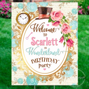 May include: A welcome sign for a birthday party with a whimsical Alice in Wonderland theme. The sign features a gold oval frame with a pink heart, a top hat, and a pocket watch. The text reads "Welcome to Scarlett in Wonderland Birthday Party".