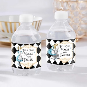 Puede incluir: Dos botellas de agua de plástico transparente con etiquetas a cuadros negros y blancos con personajes de Alicia en el País de las Maravillas. Una etiqueta dice "This One Makes You Taller" y la otra dice "This One Makes You Smaller".