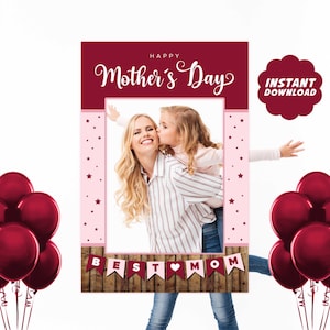 Puede incluir: Un accesorio de cabina de fotos imprimible con un marco rosa y burdeos con el texto "Feliz Día de la Madre" y "Mejor Mamá" con un corazón. El marco tiene un espacio para una foto en el centro. El fondo es blanco con globos rojos.