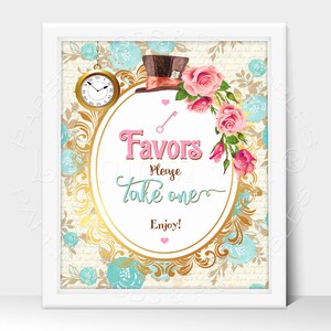 May include: A white framed sign with a gold ornate oval border and a whimsical Alice in Wonderland theme. The sign features a pink and white floral design, a Mad Hatter's hat, a pocket watch, and the text "Favors Please Take One Enjoy!"