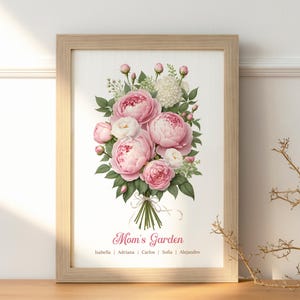 May include: A framed print featuring a bouquet of pink and white peonies with green leaves. The text "Mom's Garden" is displayed below the flowers, with names listed underneath. The frame is made of light-colored wood.