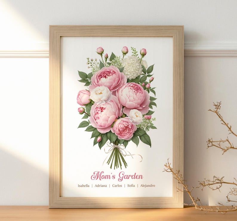 May include: A framed print featuring a bouquet of pink and white peonies with green leaves. The text "Mom's Garden" is displayed below the flowers, with names listed underneath. The frame is made of light-colored wood.