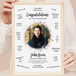 May include: A framed print featuring a photograph of a man, with congratulatory messages surrounding it. The text says "Congratulations on your promotion!" and includes the name "John Green, Creative Director."