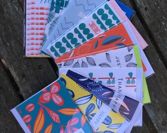 May include: A stack of colorful greeting cards with various patterns and designs. The cards feature text such as "Happy Birthday", "Happy", and "Just Than Happy".