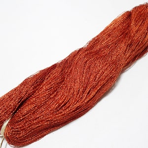 Puede incluir: Una bobina de hilo metálico naranja. El hilo está enrollado apretado y tiene un acabado brillante.