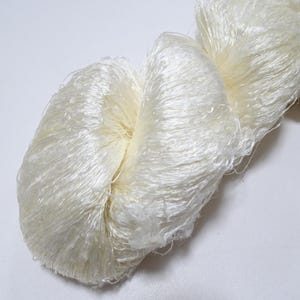 May include: A skein of white silk yarn with a soft, fluffy texture.
